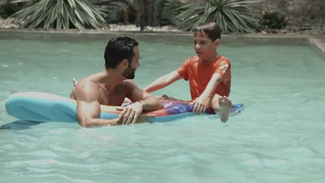 Father and son playing together in swimming pool  having fun