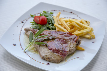 Pork steak in white plate and french fries .