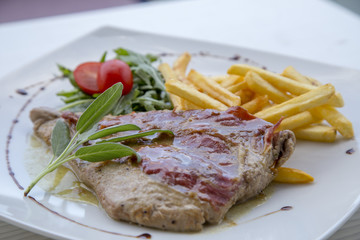 Pork steak in white plate and french fries .