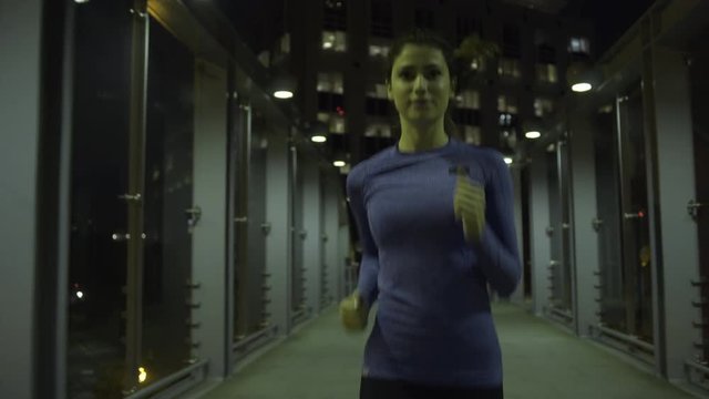 Young adult female jogging in city at night