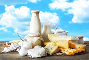 Set of fresh dairy products on wooden table, on blue sky background