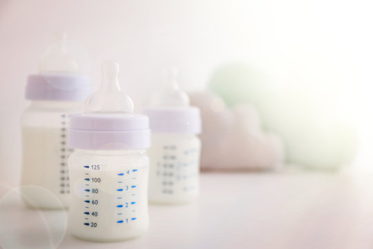 Baby milk bottles and toys on white background