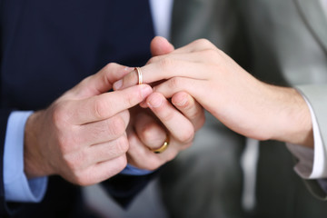 One groom placing the ring on another man's finger