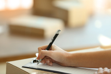 Fototapeta premium Delivery concept. Woman signs papers among parcels, close up