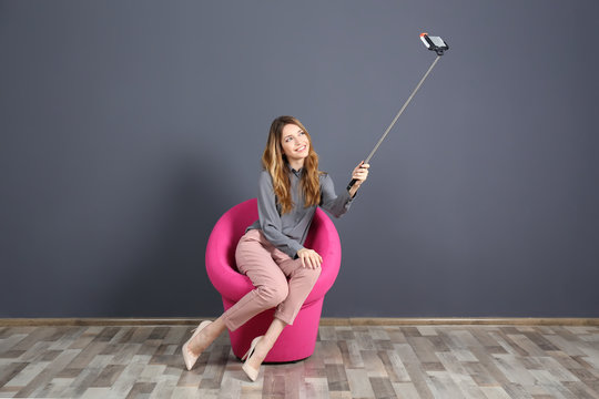 Young Attractive Woman Taking Selfie On Pink Chair In The Room