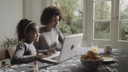 Mother with daughter teaching on laptop in kitchen - Powered by Adobe