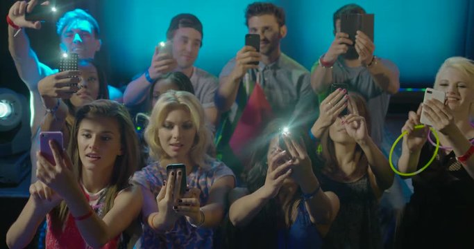 Friends taking self photograph with mobile phone in nightclub