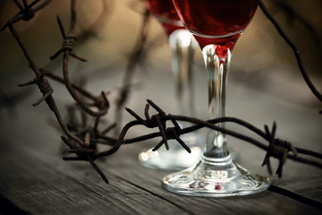 Rusty barbed wire and glasses with red wine.