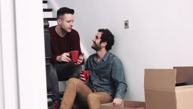 Same sex couple moving in new house, drinking coffee