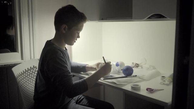 Teenager boy in bedroom painting globe