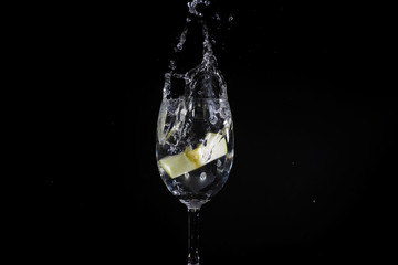 Toss fruit into a glass of splash water and black background