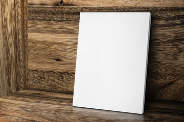 Blank white canvas frame leaning at wood wall and floor, Mock up