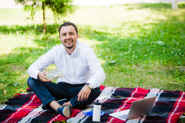Young and attractive man relaxes in the park at lunch time