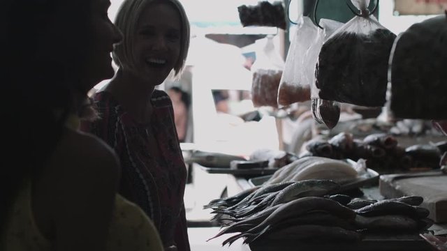 Three women talking and shopping in fish market