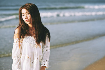 Portrait of beautiful Asian girl standing on serene beach