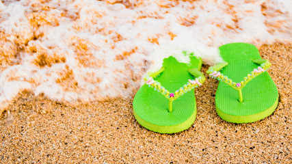 Fototapeta na wymiar Womens green sandals at the seashore.