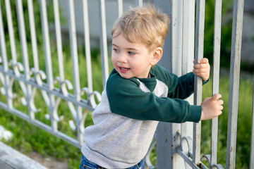 little boy climbed up on the fence