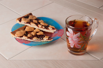 Cup of tea and plum cake with crumb on parchment paper