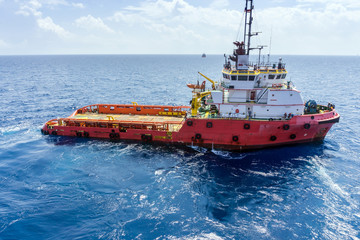 Offshore workers handling anchor to be lifted for deployment on construction barge at oilfield