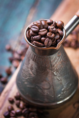 Roasted coffee beans in a cooper turk on a vintage background, closeup