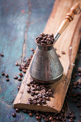 Roasted coffee beans in a cooper turk on a vintage background, copy space