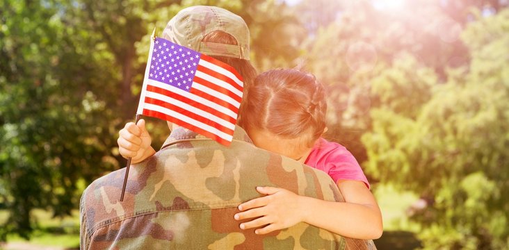 Army man hugging daughter with American flag