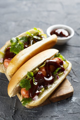 Hot dog with pickled cucumber, red onion and barbecue sauce