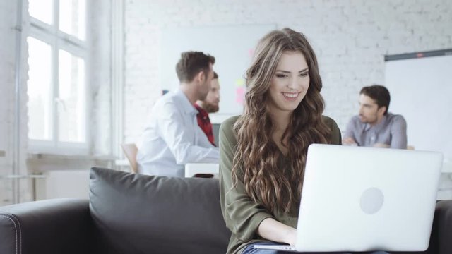 Happy young woman working on laptop in office