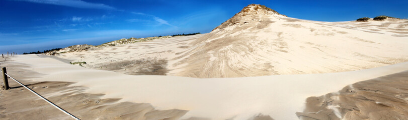 Panoramic image of sand dunes and blue sky