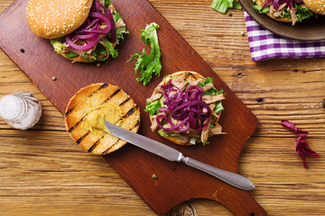 Burger with meat of duck with red onion and lettuce.