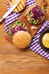 Burger with meat of duck with red onion and lettuce.