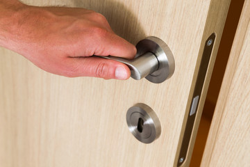 Male hand opening a wooden door