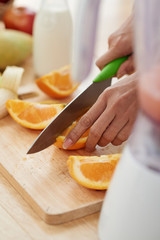 Obraz na płótnie Canvas Female hands cutting fresh juicy oranges on board