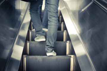 Low angle male feet walking in sneakers up escalator.