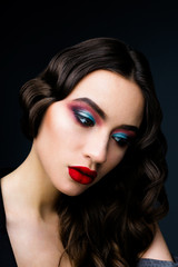 Fototapeta premium Beautiful young woman in the studio on a black background in the plan in the style of the 20s, vintage, closeup portrait with red lips 