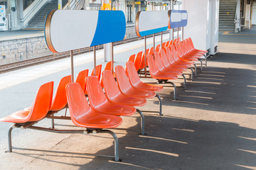 Rows of an empty orange plastic seats in railway station.