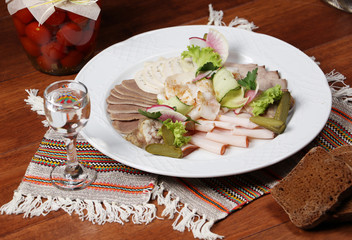 Plate of different meat cuts with bread and vodka