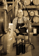 Fototapeta na wymiar Man wearing apron using bottle corking apparatus