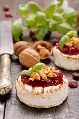 Fototapeta na wymiar Grilled brie cheese with cranberry jam and walnuts on old wooden