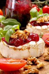 Grilled brie cheese with cranberry jam and walnuts on old wooden