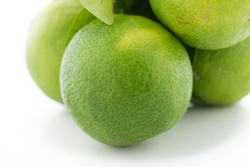 green lemon or lime with leaf on a white background.

