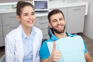 Happy young man in a dentist's chair giving a thumbs up.