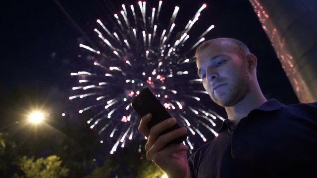 man use smart phone , image of firework as a background.