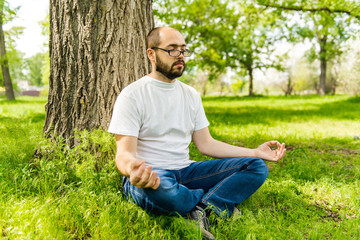 Naklejka na ściany i meble Man meditating under a tree.