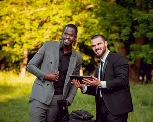 Two young businessman at work in the park.