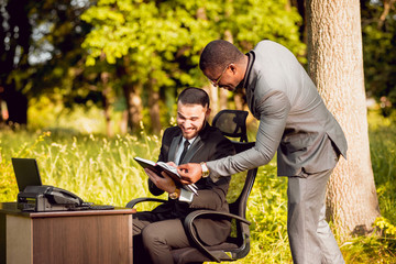 Two young businessman at work in the park.