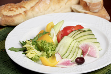 Plate with vegetables with bread on the background