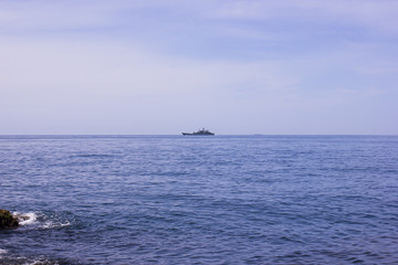 Blue sea surface with waves, sky and a ship on the horizon. Summer seascape