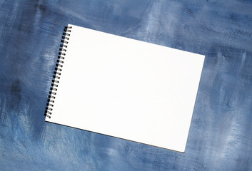 Sketchbooks with clean white pages on background of blue paint canvas