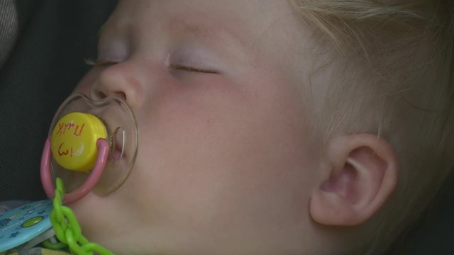 Kid is sleeping and sucking a pacifier